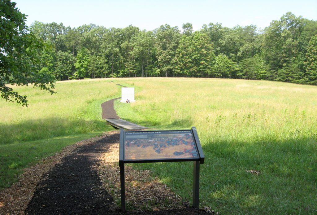 Trail through Saunders Field, with the First Blood in Saunders Field wayside marker and the monument to the 140th New York Volunteer Infantry Regiment